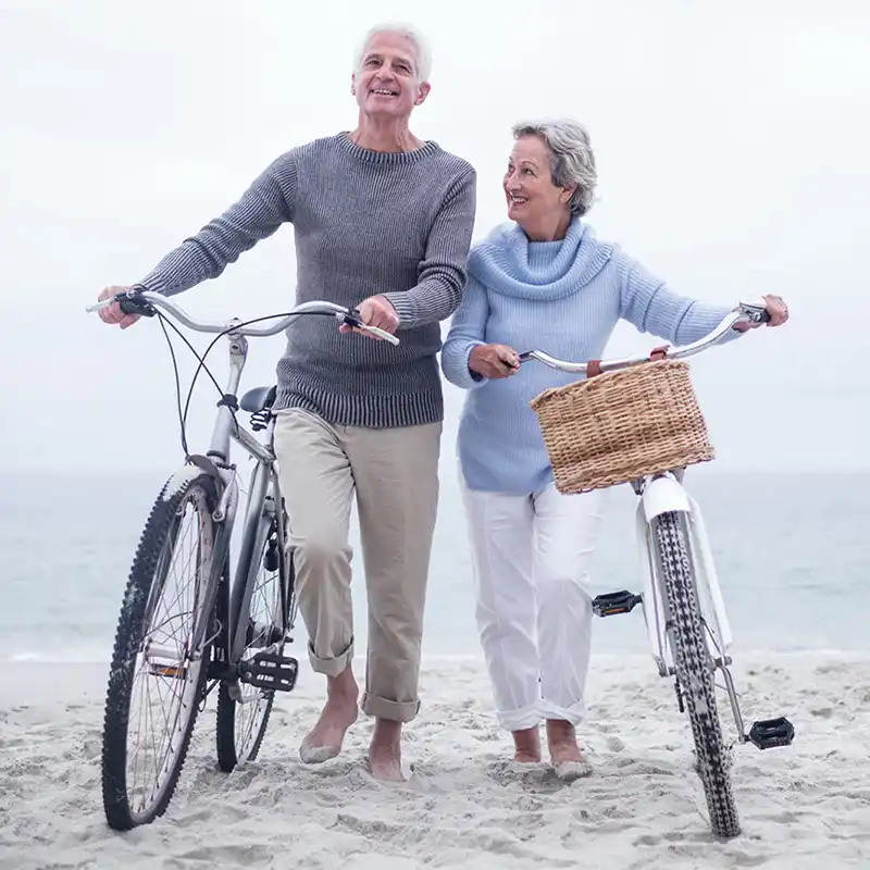 Smart Health Insurance senior couple walking bikes on the beach